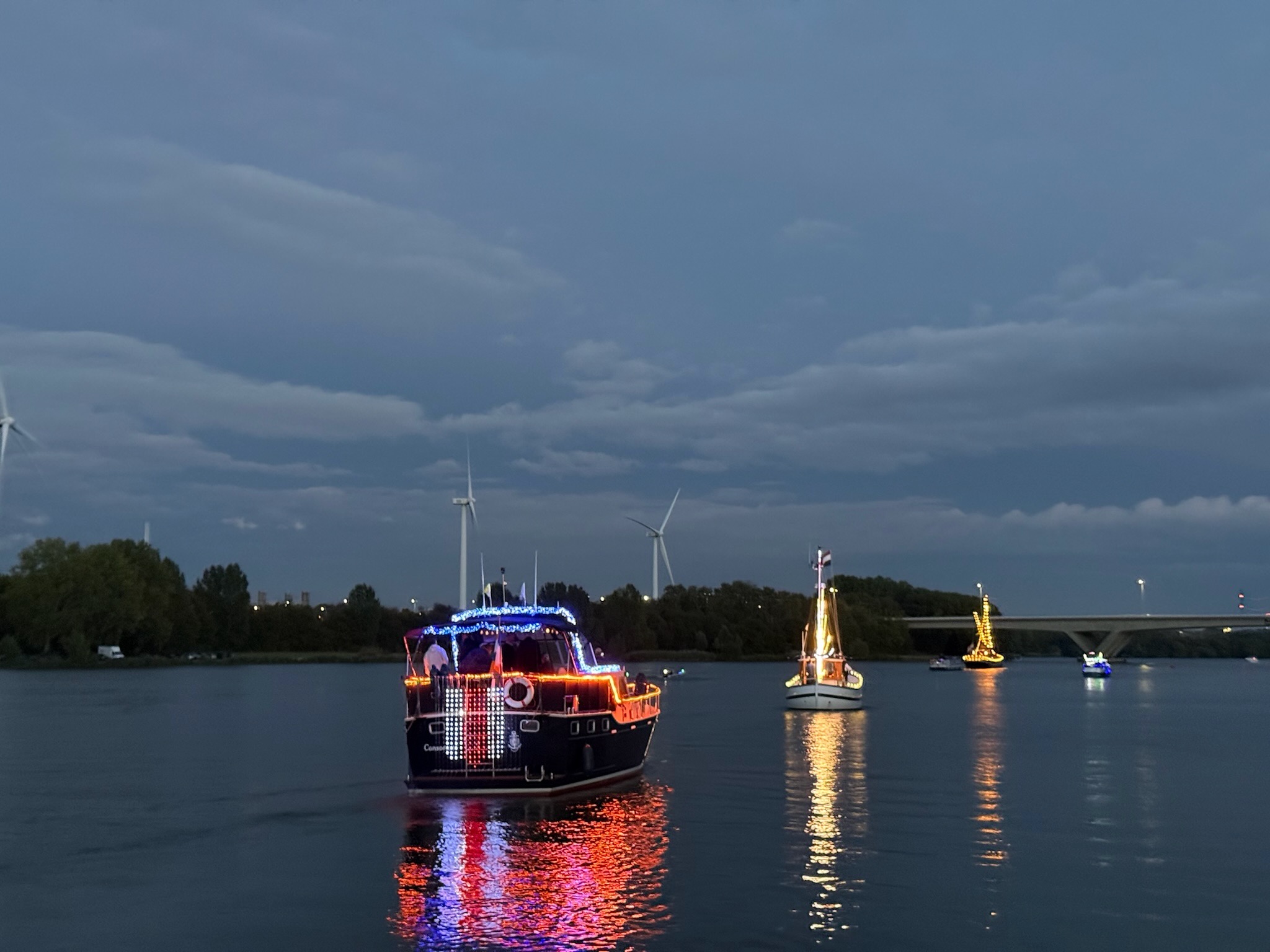 Verlichte boten varen in de avond over de Brielse Maas